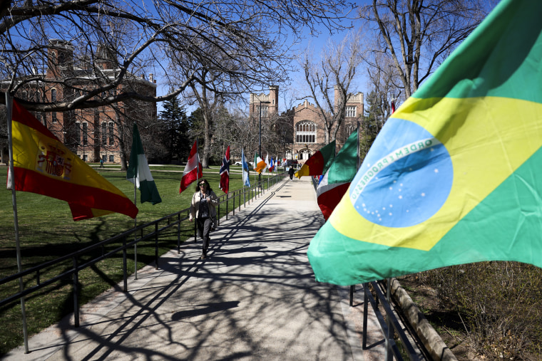 Students walk past flags on the University of Colorado campus