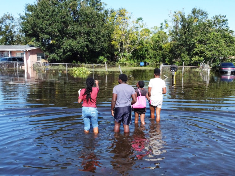 Residents wade through water to get to their house in Orlando