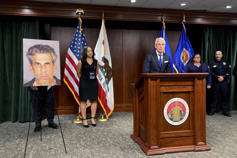 Los Angeles District Attorney George Gascon, at podium stands by a photo on display of TV producer Eric Weinberg during a news conference to announce sexual assault charges against Weinberg on Wednesday, Oct. 5, 2022 in Los Angeles.