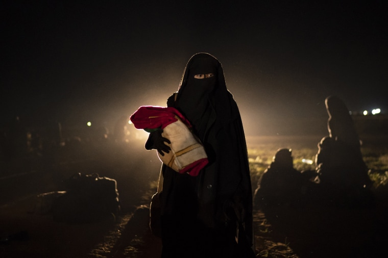 A woman and her baby, who were evacuated from the last territory held by Islamic State militants, walk after being screened by U.S.-backed Syrian Democratic Forces (SDF) in the desert outside Baghouz, Syria, on Feb. 25, 2019.
