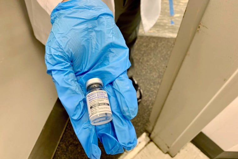 A nurse shows a patient the newly formulated Moderna bivalent Covid vaccine