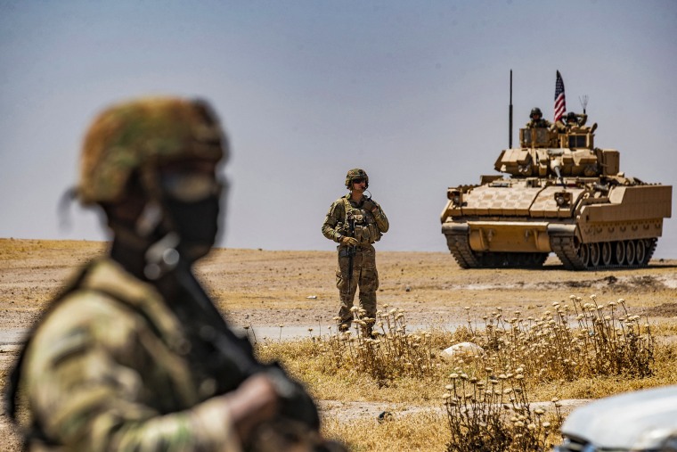 An American soldier stands near a Bradley Fighting Vehicle during a patrol near the Rumaylan oil wells in Syria's northeastern Hasakeh province.