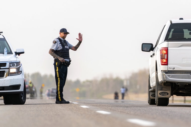 A Royal Canadian Mounted Police office gestures towards a driver on a road outside Rosthern, Saskatchewan on Wednesday, Sept. 7, 2022. Canadian police arrested Myles Sanderson, the second suspect in the stabbing deaths of multiple people in Saskatchewan, after a three-day manhunt that also yielded the body of his brother fellow suspect, Damien Sanderson.