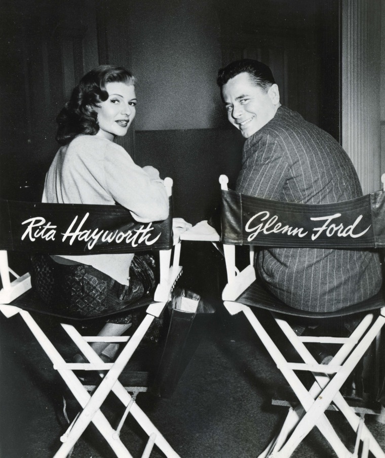Rita Hayworth sits next to actor Glenn Ford on the set of Gilda