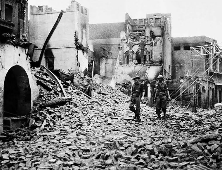 Indian soldiers walk through the debris of a building in the Chowk Bijli Wala area of Amristar during unrest following the Partition of India and Pakistan, August 1947.
