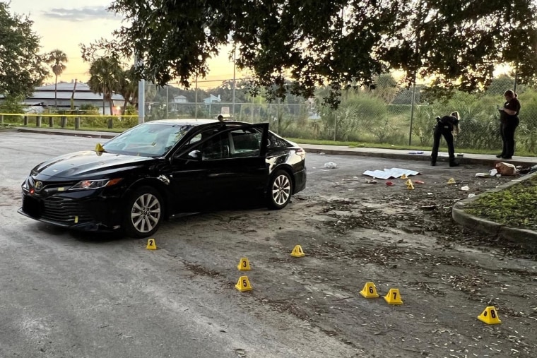 Crime scene investigators place evidence markers around a vehicle after a man fired shots at a sleeping family Wednesday in Tampa, Fla. 
