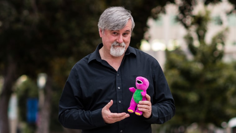 Bob West holding a Barney plush doll.