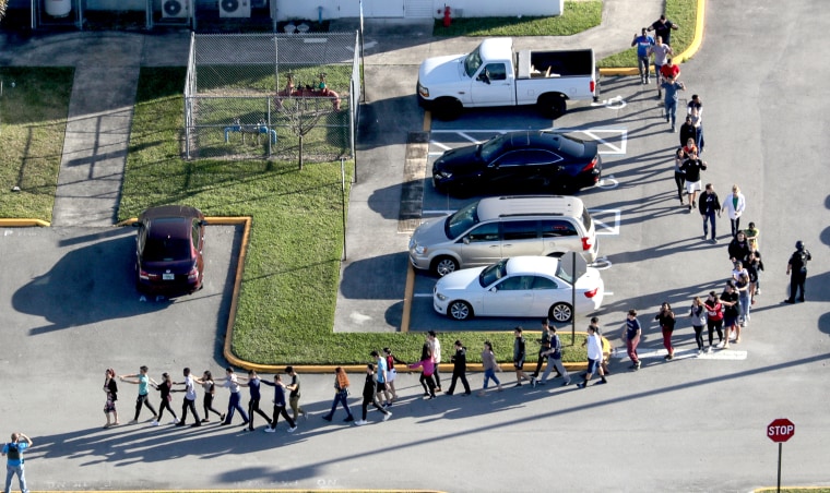 Students are evacuated by police out of Marjorie Stoneman Douglas High School in Parkland, Fla., after a shooting on Feb. 14, 2018.