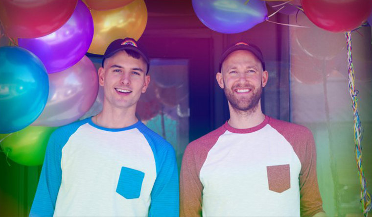 Nicholas Ruiz and Casey Fitzpatrick. smiling in front of colorful balloons.