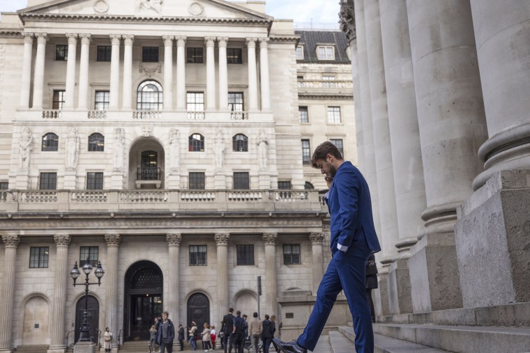 A man stands on the steps of the Royal Exchange in front of the Bank of England