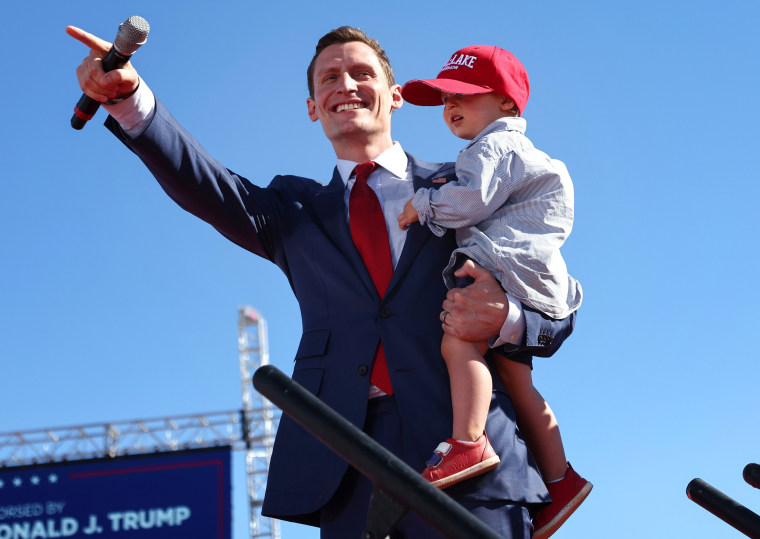 Image: Blake Masters carries 2-year-old son Rex to the stage at a campaign rally, in Mesa, Ariz