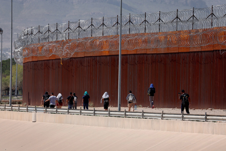 Migrants walk along the U.S.- Mexico