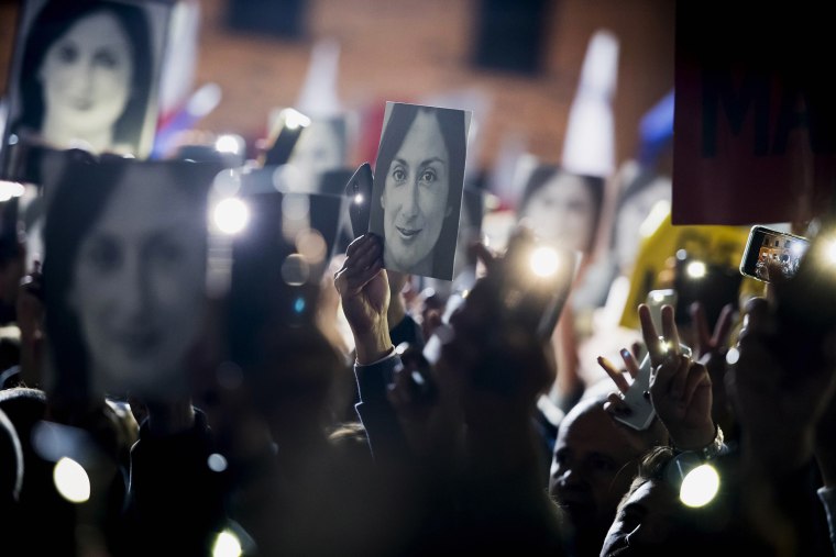 People hold pictures of slain journalist Daphne Caruana Galizia