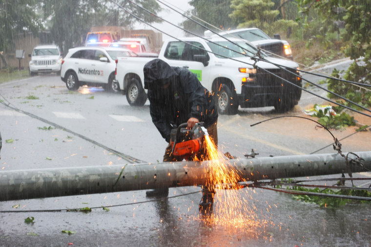 A worker cuts an electrical pole that was downed by Hurricane Fiona as it blocks a road in Cayey, Puerto Rico.