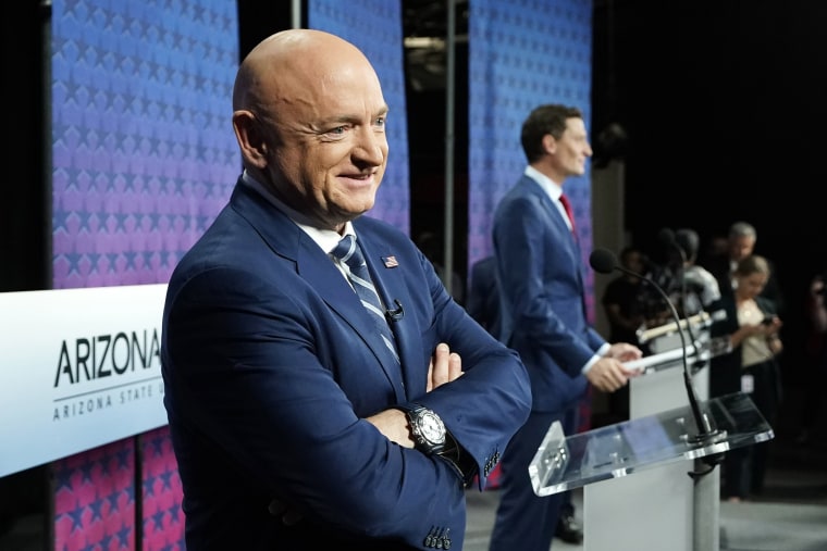 Mark Kelly, left, smiles as he stands on stage with Blake Masters, right, prior to a televised debate in Phoenix