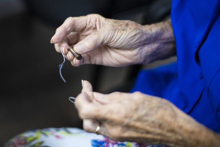 A woman holds her hearing aid as she visits Hear Again America for a checkup on Oct. 20, 2021 in Fort Lauderdale, Fla.