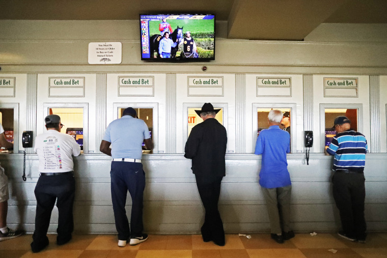 Gamblers stand at betting windows