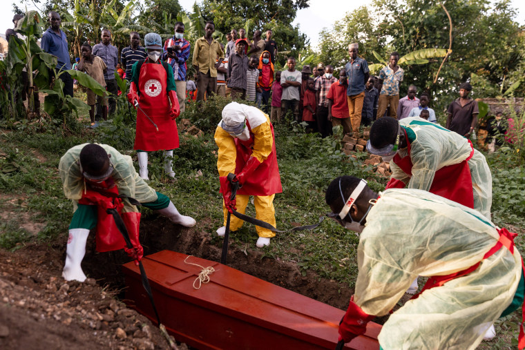 Ugandan Red Cross workers place a coffin, containing an Ebola victim, into a grave during a Safe and Dignified Burial