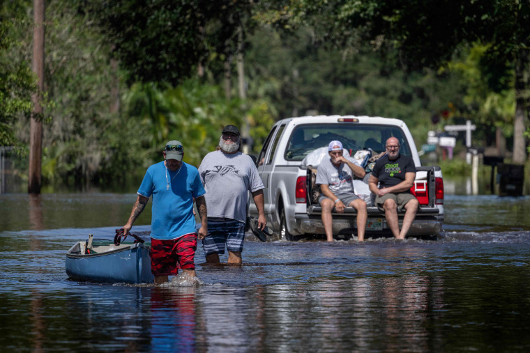 A man tows a canoe through a flooded street in New Smyrna Beach, Florida