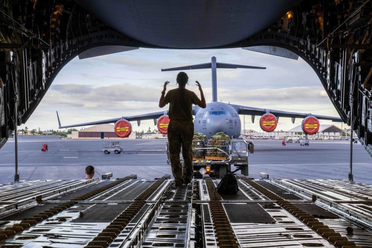 A female service worker directs a k-loader loading cargo for an airdrop exercise at Joint Base Pearl Harbor-Hickam, Hawaii.