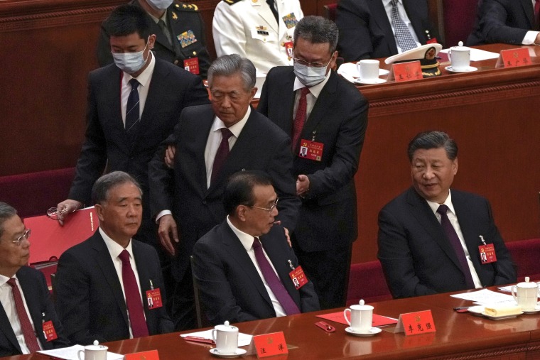 President Xi Jinping, right, looks on as former Chinese President Hu Jintao, is assisted to leave the hall.