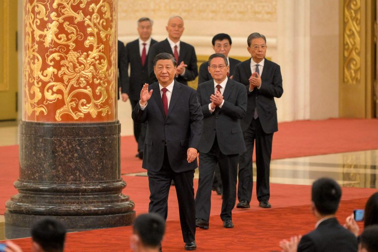 China's President Xi Jinping (front) walks with members of the Chinese Communist Party's new Politburo Standing Committee as they meet the media in the Great Hall of the People in Beijing on October 23, 2022. Xi broke with tradition by staying in power for a third term.