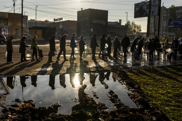 People queuing up hold plastic bottles to refill drinking water from a tank in the center of Mykolaiv, Ukraine, on Oct. 24, 2022.
