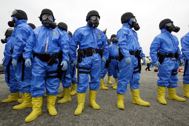 Police officers in hazard suits secure the scene in a "hazardous material hot area" after the explosion of a "dirty bomb" during a simulated attack at a dock at the Port of Los Angeles on Aug. 5, 2004.
