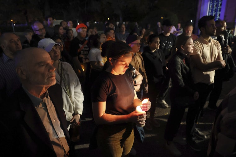 Marie Crane, center, holds a candle during a vigil for the victims of a school shooting at Central Visual & Performing Arts High School in St. Louis on Monday, Oct. 24, 2022. 