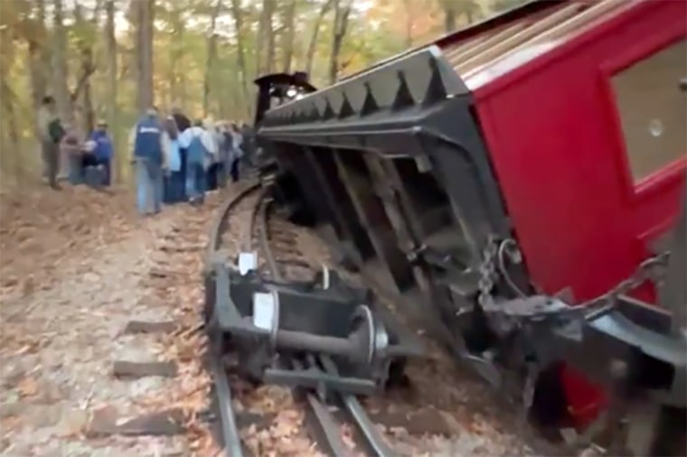 People walk near a derailed train at Missouri’s Silver Dollar City amusement park Wednesday.