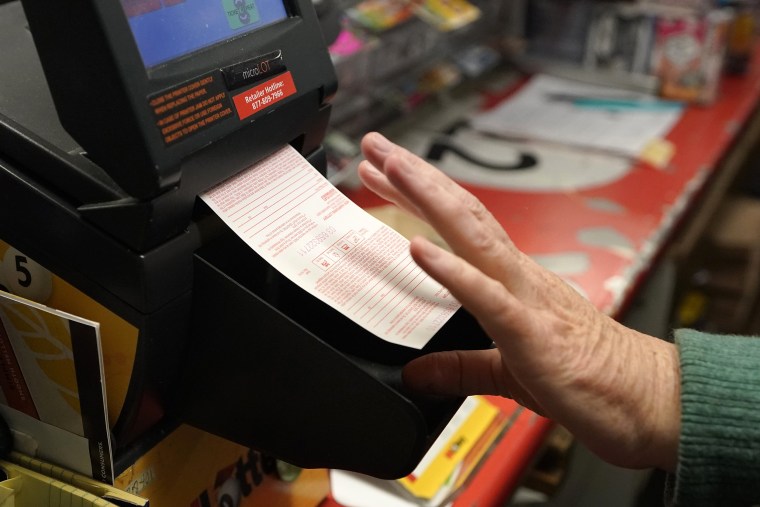 Beth Cote, of Nashua, N.H., removes a sold Powerball ticket as it is dispensed from a machine for a customer, Wednesday, Oct. 26, 2022, at Bright Spot convenience store, in Nashua. The eighth-largest lottery jackpot will be up for grabs when numbers are drawn for an estimated $700 million Powerball grand prize.