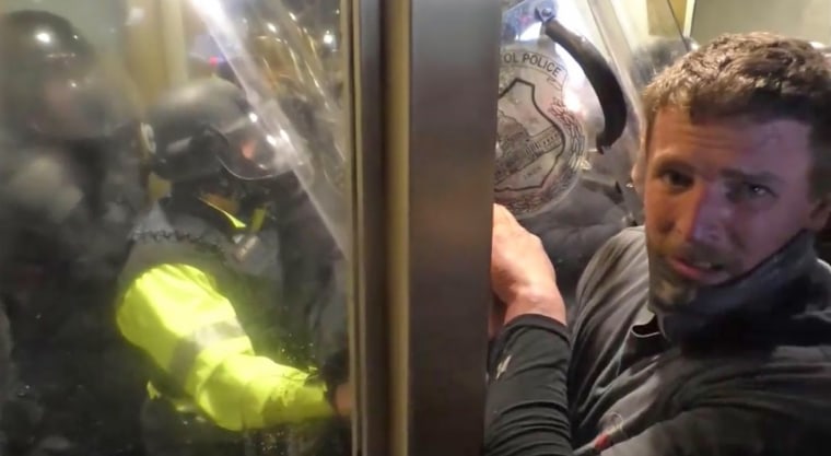 Albuquerque Head, right, is pushed back by police officers toward the mouth of a tunnel at the U.S. Capitol on Jan. 6, 2021.