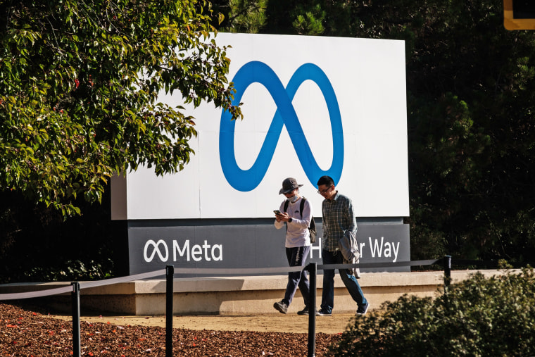 People walk past the Meta logo outside the company's headquarters