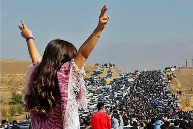 An unveiled woman stands on top of a vehicle as thousands make their way towards Aichi cemetery in Saqaez, Mahsa Amini's hometown in Iranian Kurdistan, to mark 40 days since her death, on Oct. 26, 2022.