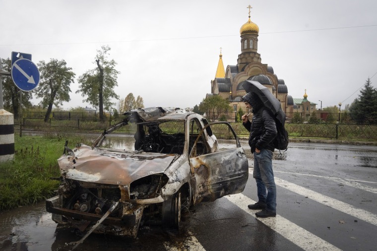 A passerby looks at a car damaged by Russian shelling in Bakhmut, Ukraine, on Oct. 26, 2022. 