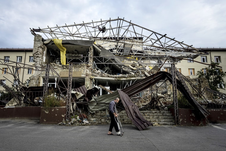 A patient walks past a hospital that was destroyed after a Russian attack 