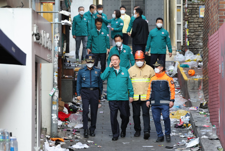 South Korean President Yoon Suk Yeol, center left, visits the scene where 151 people died and dozens were injured in Seoul, South Korea, Sunday, Oct. 30, 2022.