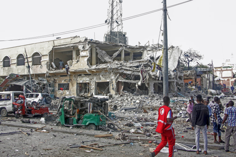 People observe a destroyed building and vehicles at the scene of two explosions in Mogadishu, Somalia, on Saturday Oct. 29, 2022. 