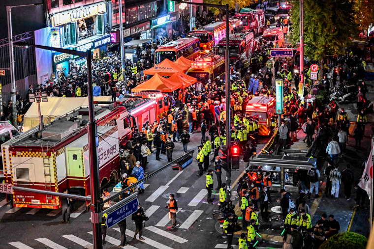 Onlookers, police and paramedics gather where more than 150 people died in Seoul's Itaewon district on Oct. 30, 2022.