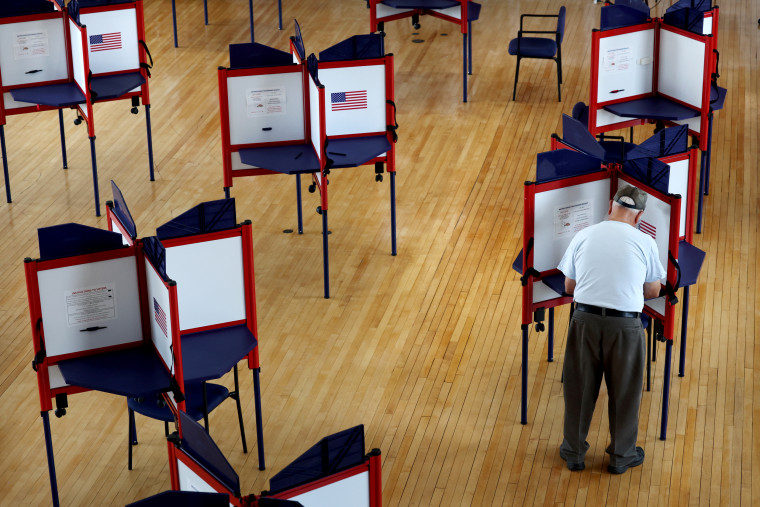 Image: A voter fills out a ballot during early voting in Quincy, Mass., on Aug. 27, 2022.