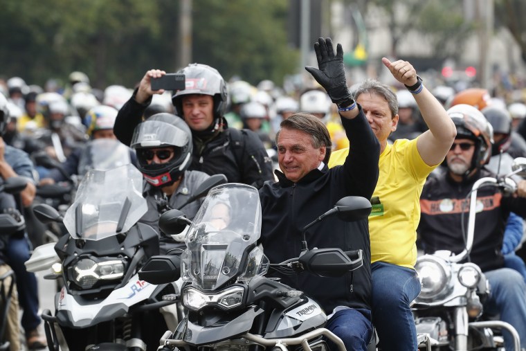 El presidente de Brasil y actual candidato a reelección, Jair Bolsonaro (en el centro), acompañado del candidato a gobernador de Sao Paulo, Tarcísio Gomes de Freitas, participa en una caravana de motocicletas organizada por sus simpatizantes en Sao Paulo, previo a los comicios presidenciales.