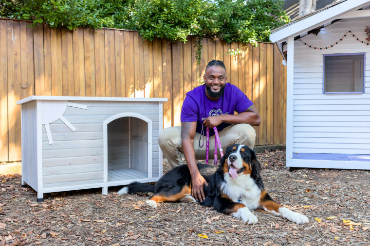 James Smith-Williams bonds with a canine pal near a doghouse he helped build and paint at a domestic violence shelter. 