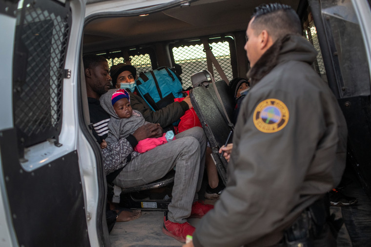 Inmigrantes de Haití y Venezuela esperan ser transferidos por agentes del alguacil a un centro de procesamiento de la Patrulla Fronteriza de EE.UU. el 11 de diciembre de 2021 en Yuma, Arizona.
