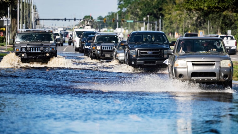 Autos atraviesan las aguas de las inundaciones mientras regresan a New Smyrna Beach, Florida, el 30 de septiembre de 2022, después de que el huracán Ian azotara la zona.