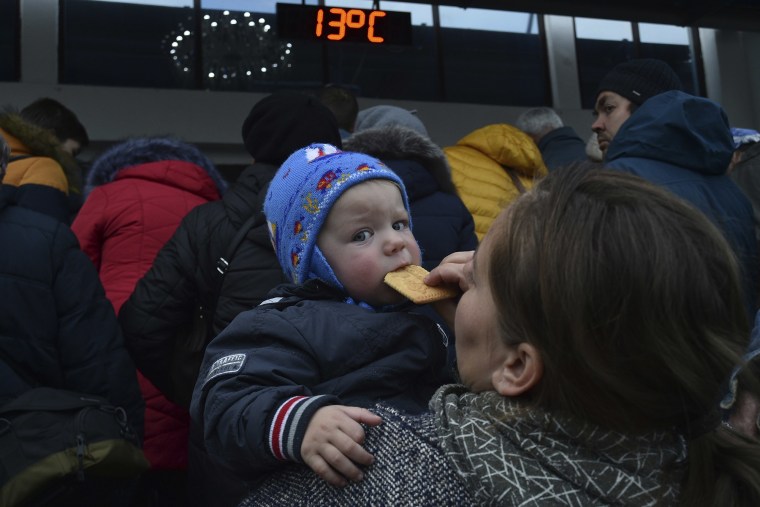 Una mujer sostiene a su hijo entre un grupo de evacuados de Kherson que se reúnen en la estación de tren en Dzhankoi, Crimea, el viernes 21 de octubre de 2022.