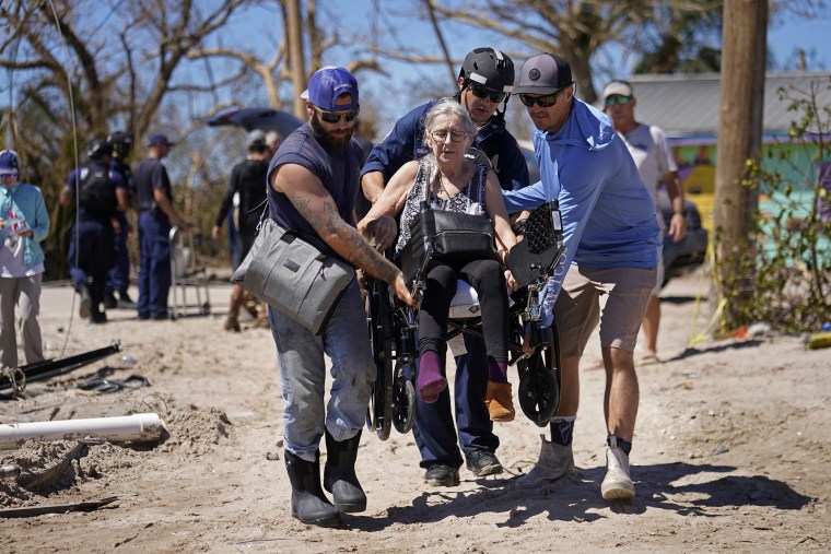 Los rescatistas ayudan a evacuar a Suzanne Tomlinson, una residente que sobrevivió a la tormenta, mientras la llevan a un bote que la espera después del huracán Ian en Pine Island en el condado Lee de Florida, el domingo 2 de octubre de 2022.
