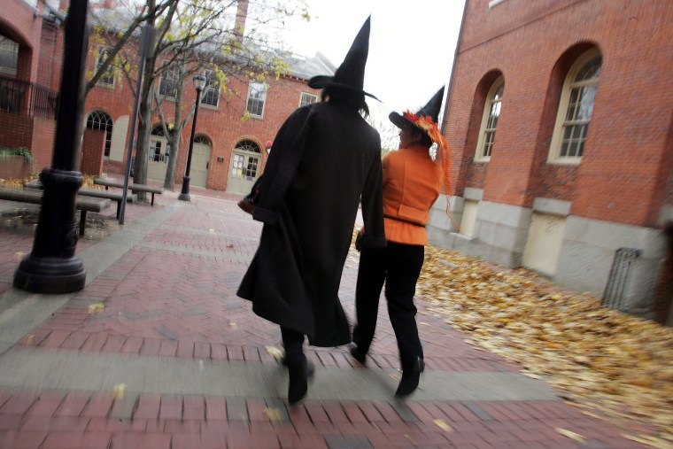 People dressed as witches on the street next to the old Town Hall where the witch trials took place in Salem, MA.