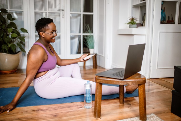 Woman working out at home while watching online yoga class.