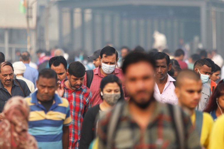 Commuters walk at Anand Vihar on a smoggy day amid