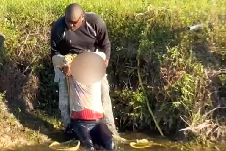 A man helps a woman out of a canal after her car was spotted from the air by a paraglider, in Florida, on Oct. 30, 2022.